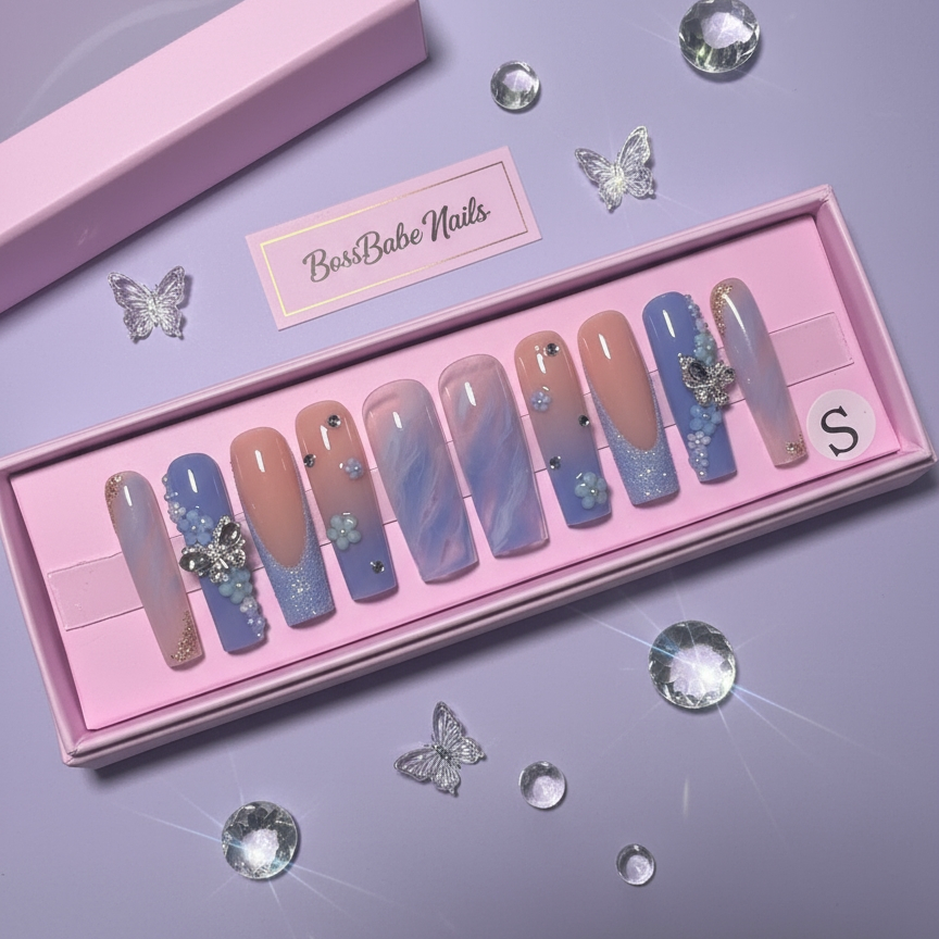 Set of decorative blue nails in a pink box with 'BessBabe Nails' branding on a purple background.